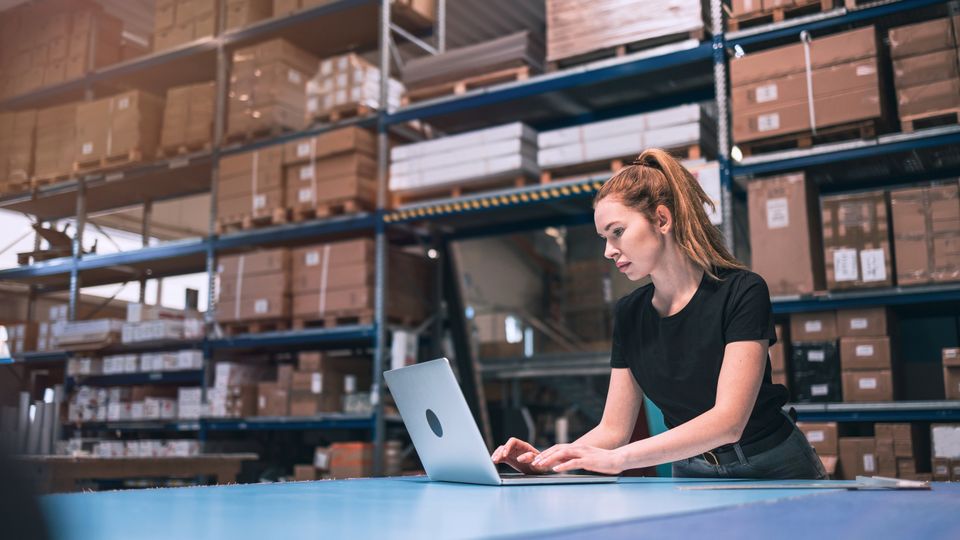 Retailprofessional met laptop in een magazijnomgeving