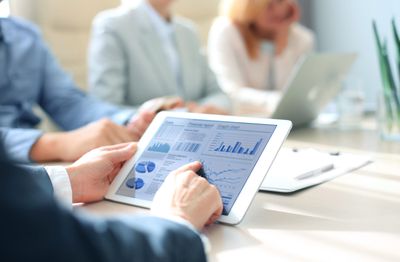 Financiële rapportages en grafieken op een tablet tijdens een analysegesprek